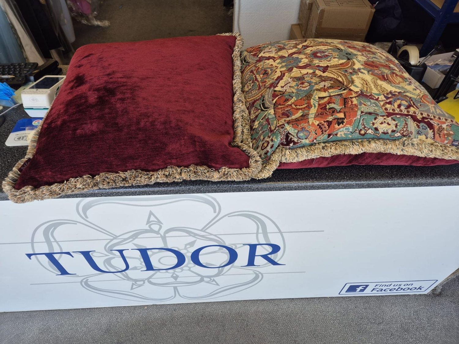 A burgundy velvet cushion and an ornate tapestry cushion, both with fringing, cleaned at Tudor Dry Cleaners